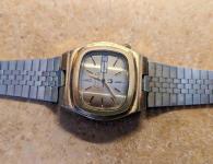 Gold, square-faced watch with Bulova Accutron text, tuning fork symbol, and date/day window