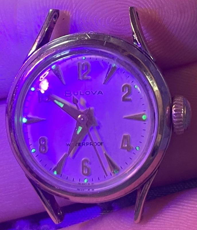 Front of watch with UV light showing luminous radium hour markers and hands